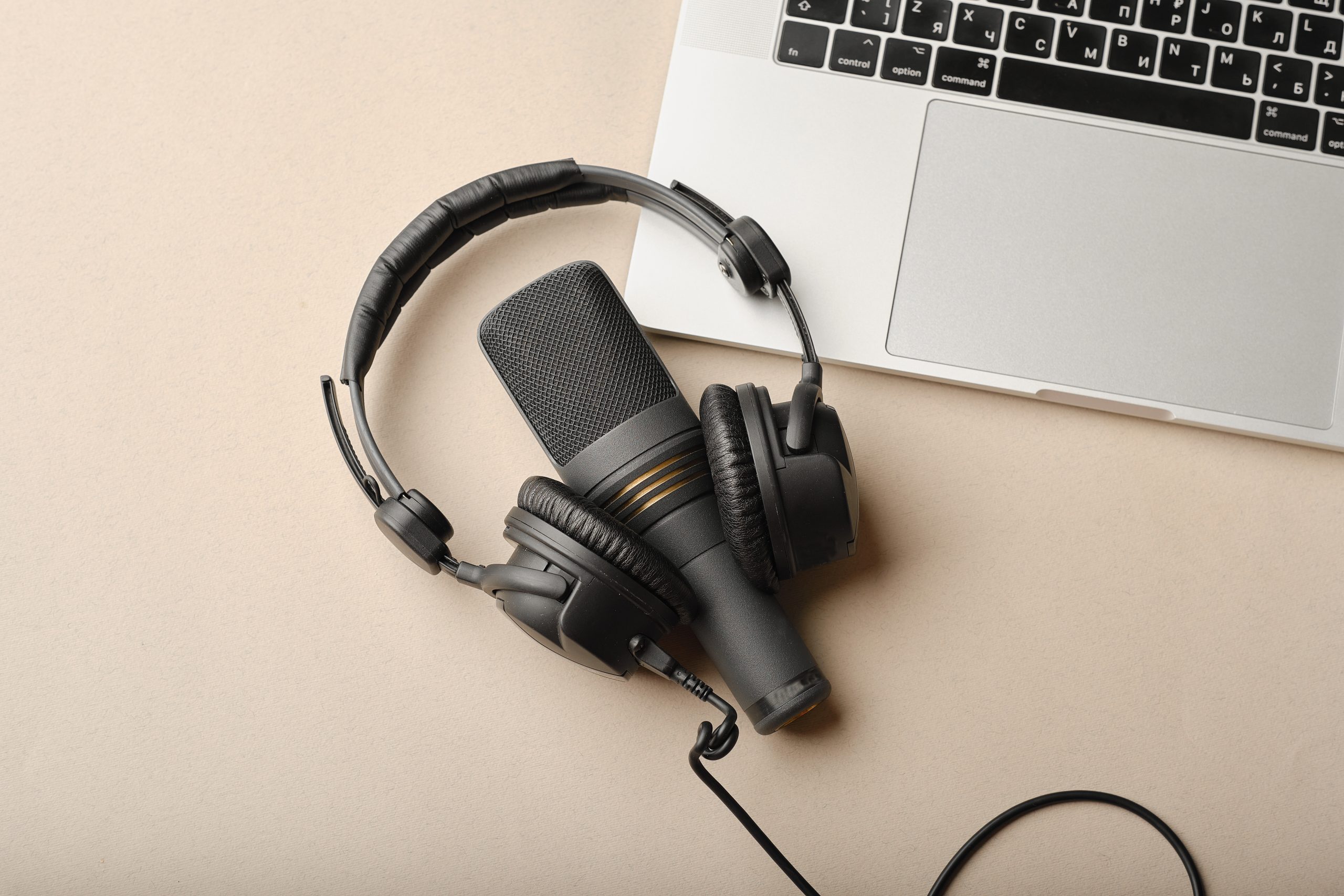 Flat lay composition with Microphone for podcasts  and black studio headphones on brown background with coffee and laptop, learning online education concept.